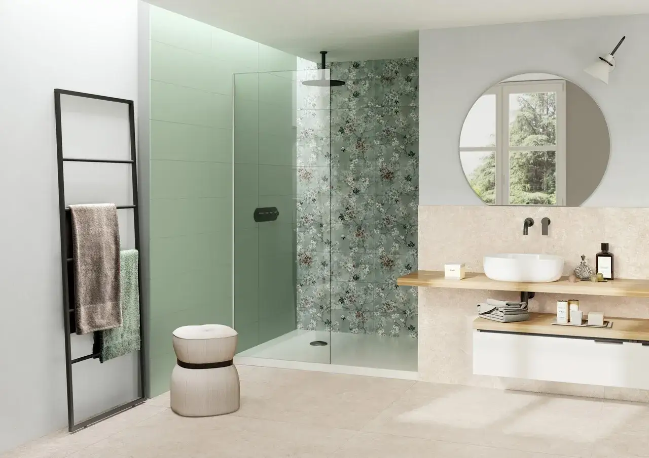 Elegante bagno verde e beige con doccia a parete floreale, lavabo sospeso e specchio rotondo.