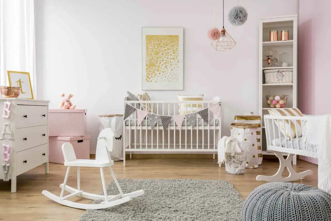 Arredamento camera neonato con lettino, cassettiera, cavallo a dondolo e decorazioni in rosa e grigio.