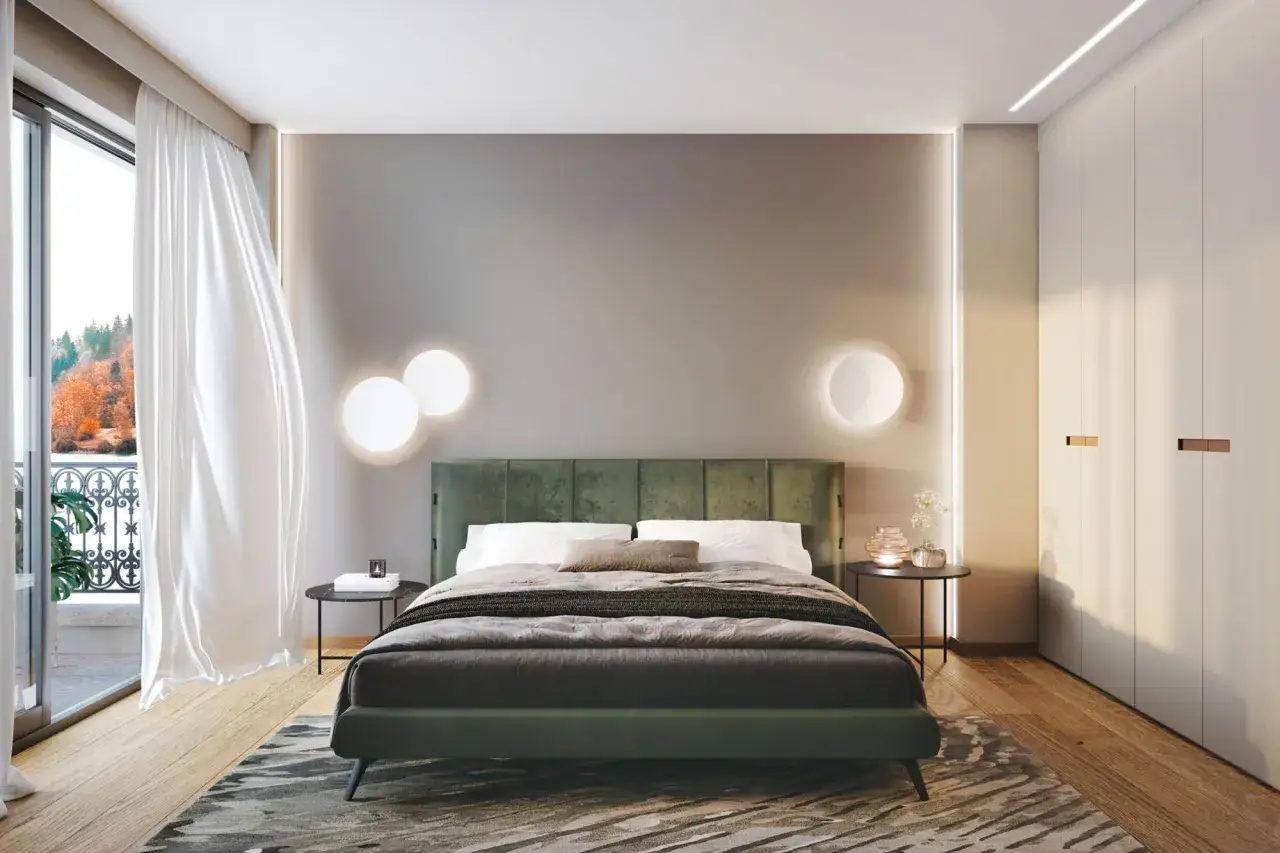 Camera da letto moderna con letto verde, luci soffuse e vista su un paesaggio autunnale. Un esempio di come illuminare la camera da letto con stile.