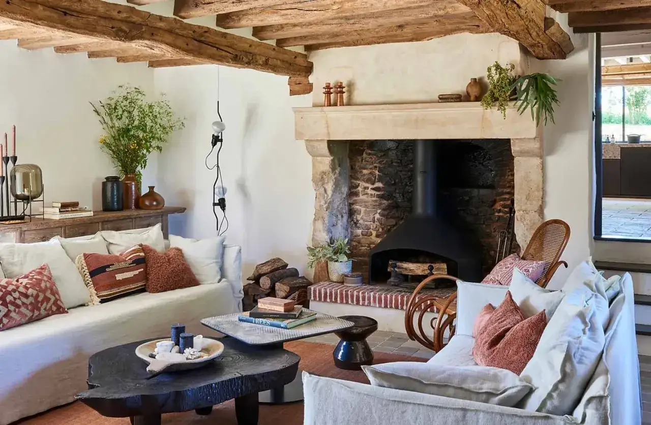 Interni accoglienti de le pi&ugrave; belle case di campagna: camino in pietra, travi a vista, divani comodi e tavolini rustici.