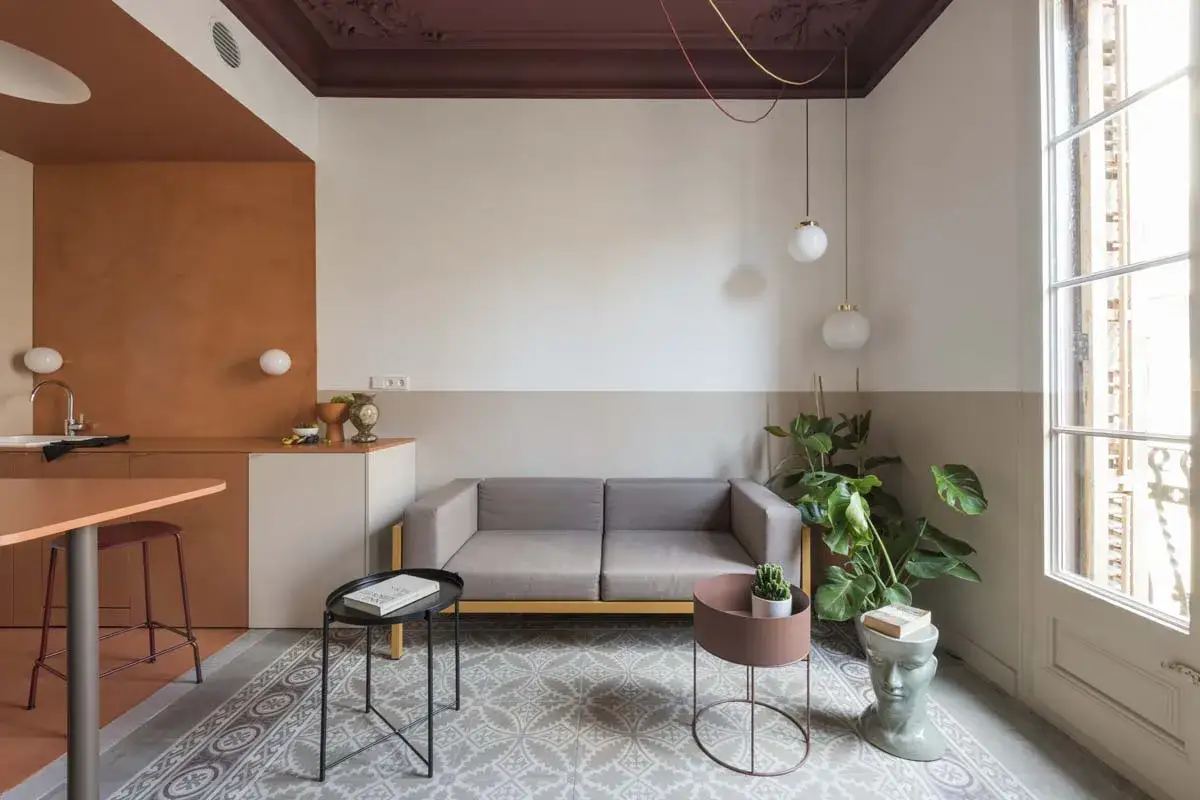 Soggiorno moderno con divano grigio, pareti bicolore e un elegante colore taupe abbinamento con arredi in terracotta.