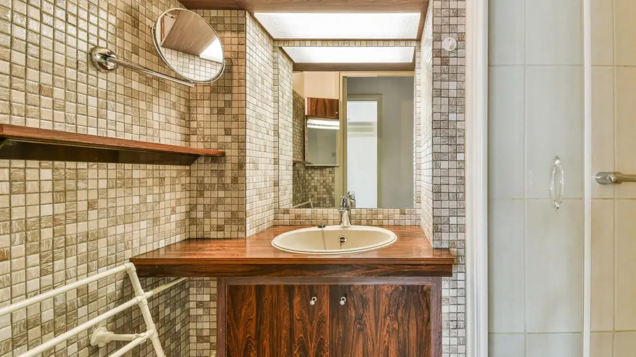 Lavabo bagno in muratura con piano in legno e mobile scuro. Idee per un bagno con mosaico e specchio.