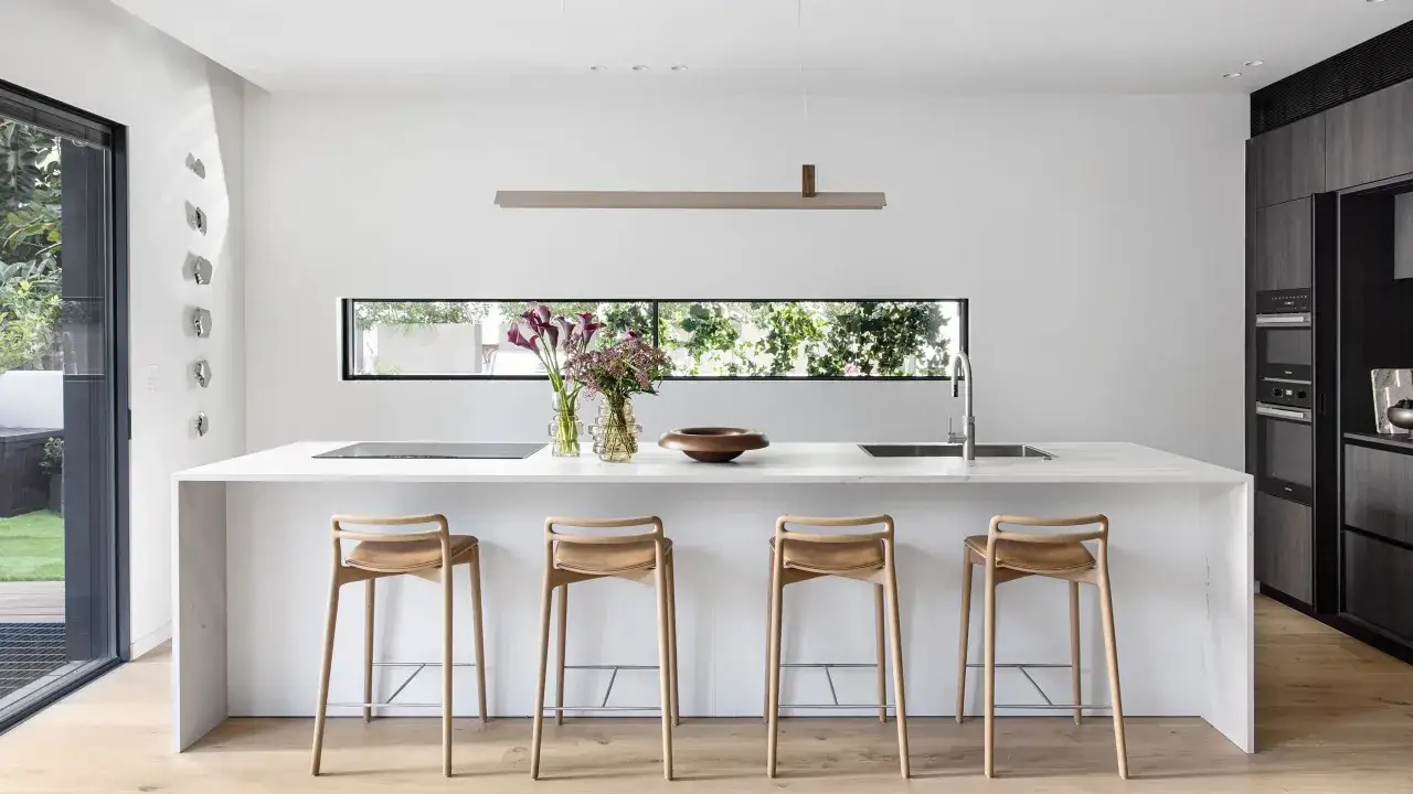 Isola cucina bianca minimalista con sgabelli in legno e fiori. Ottime idee cucina bianca per un ambiente luminoso e moderno.