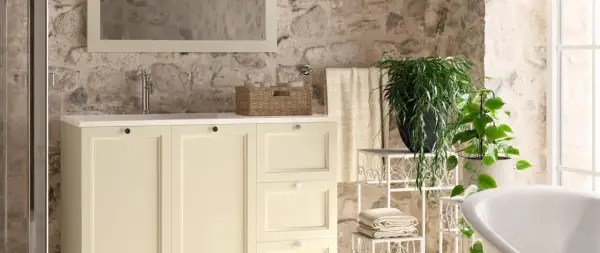 Bagni stile rustico con mobile lavabo color crema, pareti in pietra grezza e piante verdi.