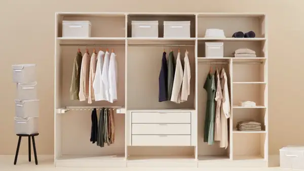 Un armadio bianco ben organizzato con vestiti appesi, scatole contenitive e cassetti.