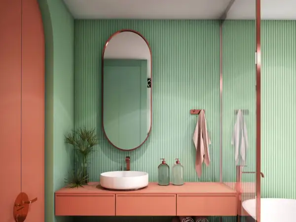 Bagno moderno con lavabo bianco, mobile color pesca e pareti verdi a coste. Idee bagni piccoli bellissimi con specchio ovale e dettagli in rame.