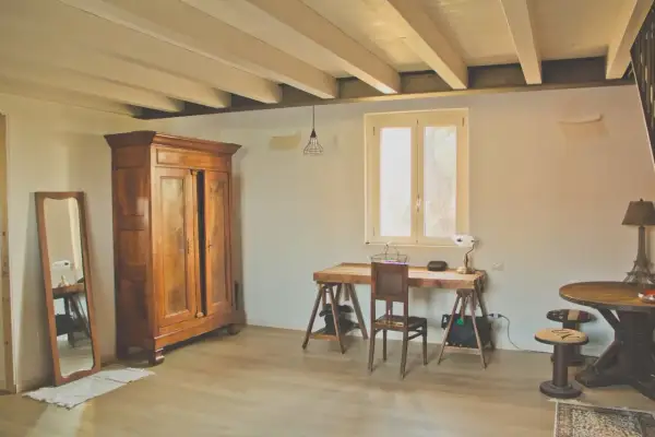 Interni di le più belle case di campagna: armadio antico, specchio, scrivania rustica e tavolino rotondo con lampada Torre Eiffel.