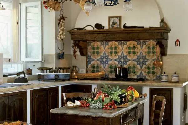 Cucine montagna piccole con un ricco tavolo di verdure fresche. Pareti decorate con maioliche colorate e dettagli rustici.