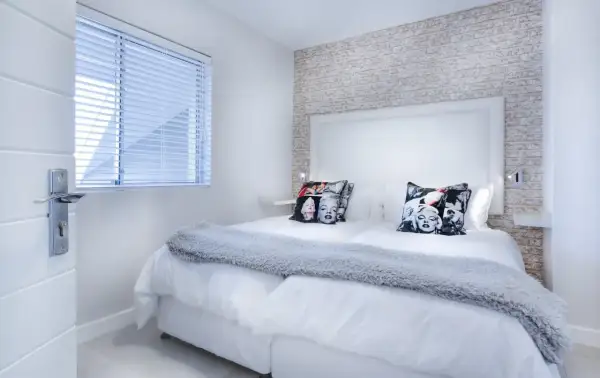 Camera da letto moderna con cuscini di Marilyn Monroe. I colori neutri e la luce soffusa creano un'atmosfera rilassante, perfetta per la cromoterapia.