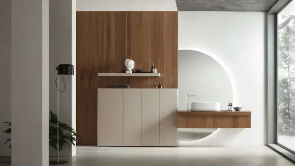 Un elegante bagno minimal con mobile sospeso in legno, lavabo bianco e specchio circolare retroilluminato.