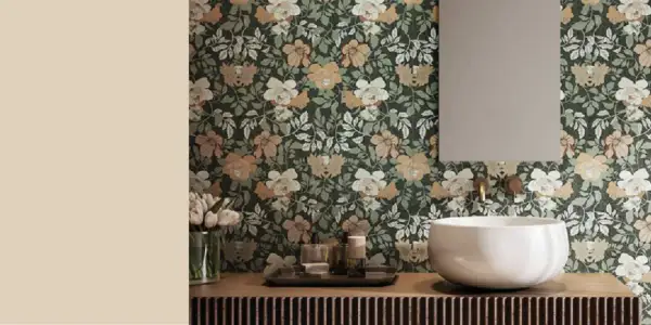 Bagno con carta da parati floreale su sfondo verde scuro, fiori bianchi e color sabbia. Lavabo bianco, specchio e rubinetteria dorata.