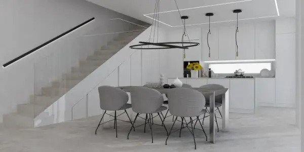 Un tavolo con sedie grigie in una moderna cucina bianca, con scala a vista e illuminazione minimalista. Perfette idee cucina bianca per un ambiente luminoso.