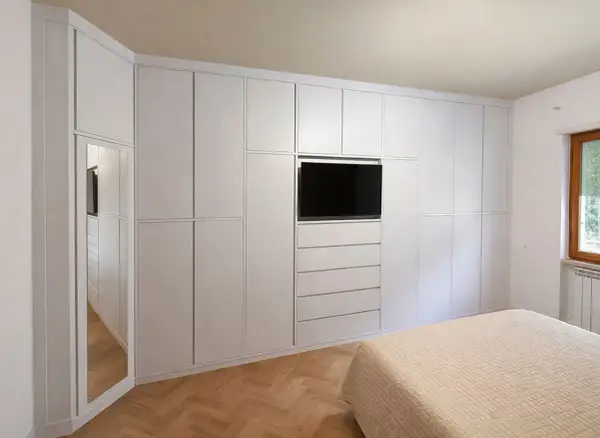 Armadio a muro bianco con TV integrata e specchio, perfetto per idee armadio camera da letto piccola.