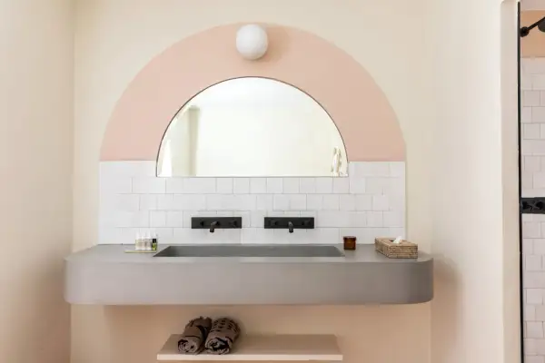 Lavabo bagno in muratura moderno con doppio rubinetto nero e specchio ad arco. Idee per un bagno di design.