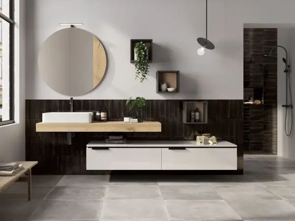 Bagno moderno con piastrelle nere verticali, lavabo bianco su mensola in legno, specchio rotondo e mobile sospeso. Idee bagno nero e legno per un look sofisticato.